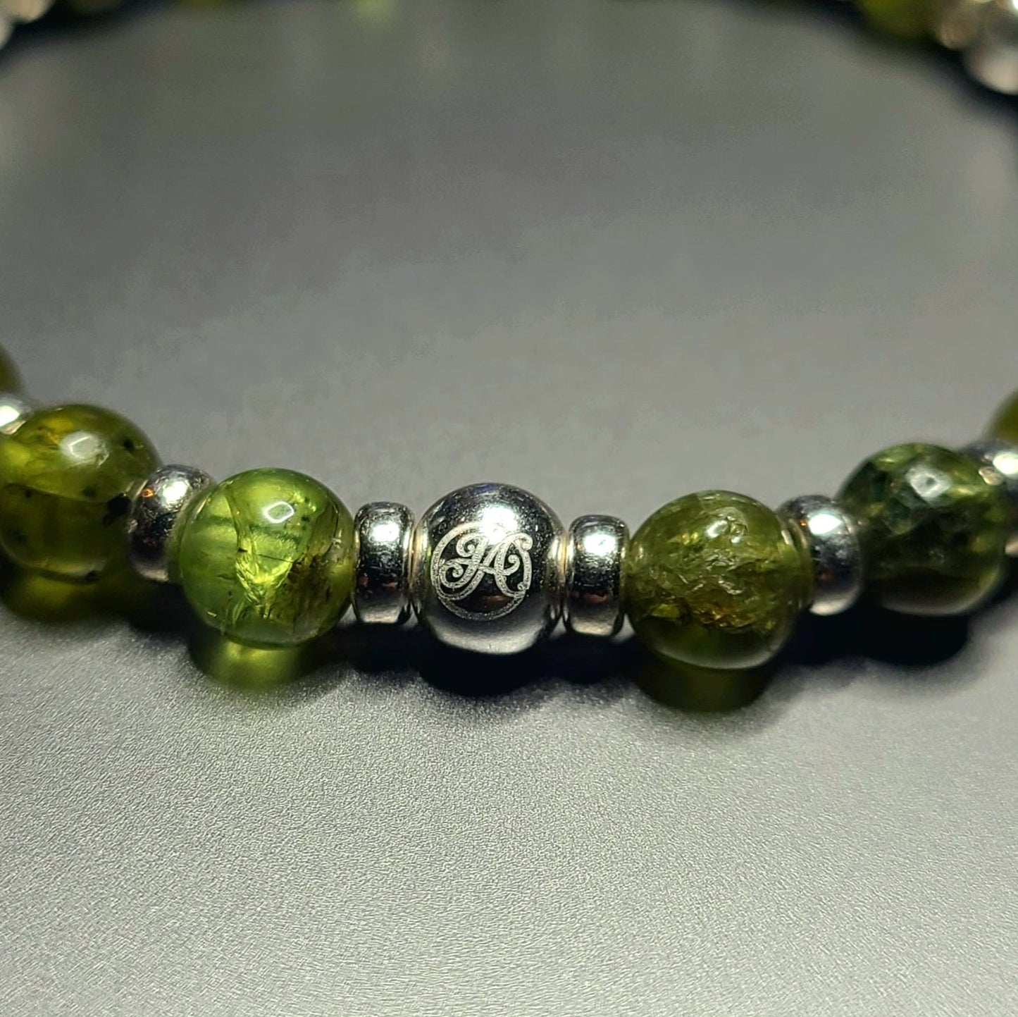 Close-up of the sterling silver John Alex signature bead and 6 mm peridot beads