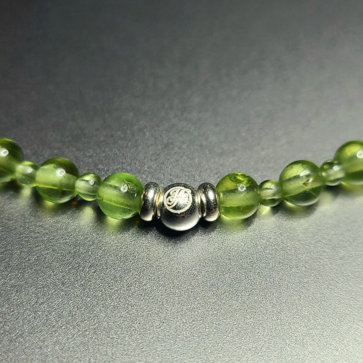 Close-up of the sterling silver John Alex signature bead with 2 mm and 4 mm peridot beads