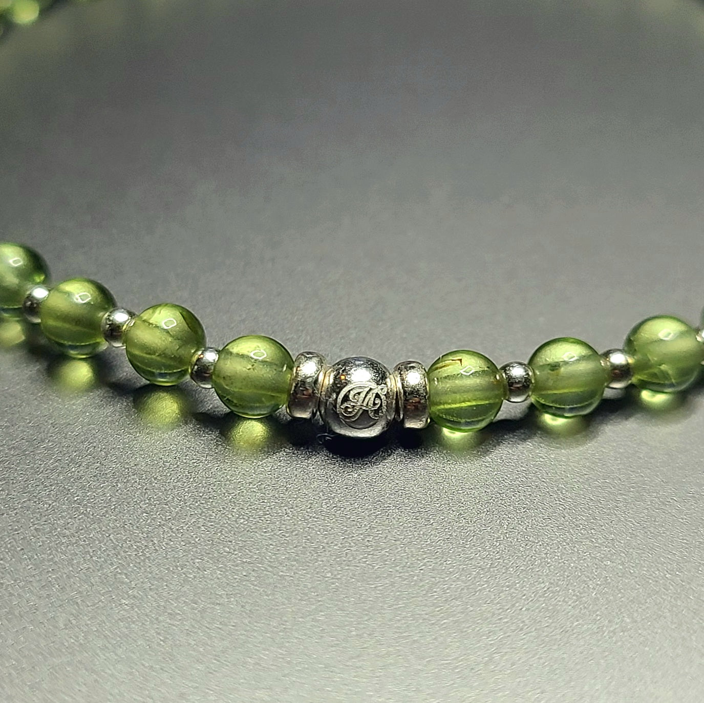 Close-up of the sterling silver John Alex signature bead with 4 mm peridot beads